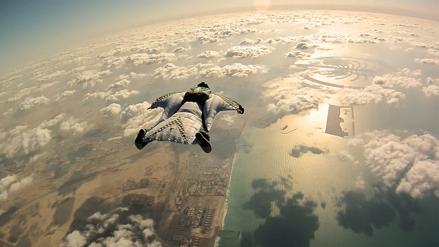 Wingsuit pilot flying high above the Dubai coastline and Palm Jumeirah